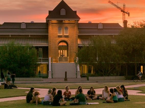 Students sitting in front of Old Main at sunset